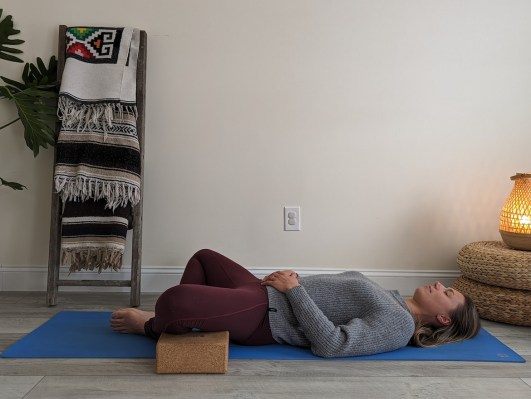 Yoga teacher demonstrating reclined bound angle pose