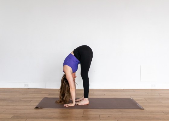 Yoga teacher demonstrating standing forward fold