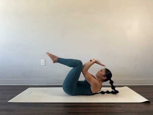 Yoga teacher demonstrating supine crow pose