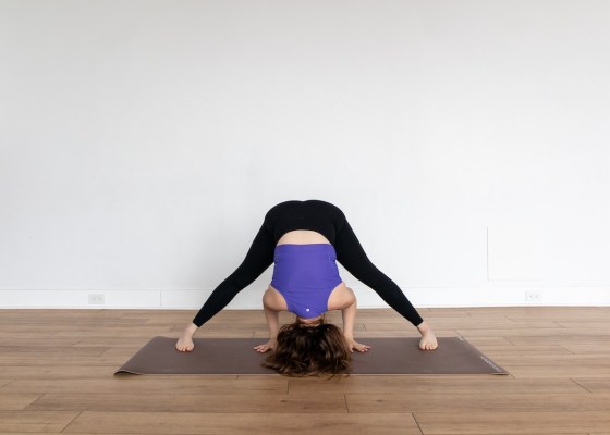 Yoga teacher demonstrating wide-legged forward fold