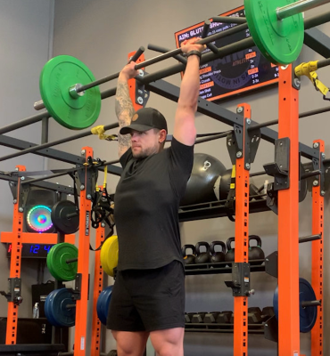 Personal trainer demonstrating barbell overhead press 