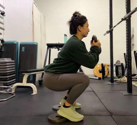 Personal trainer demonstrating heels-elevated squat
