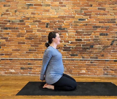Schwangere Person macht Heldenpose-Yoga