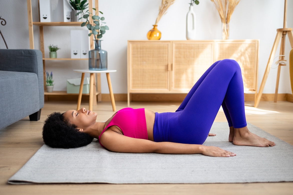Person wearing pink sports bra and blue leggings doing yoga flow lying down