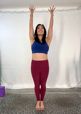 Yoga instructor demonstrating mountain pose with hands up