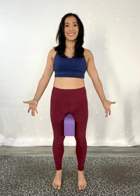 Yoga instructor demonstrating mountain pose with yoga block